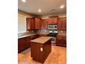 This kitchen features wood cabinets, granite countertops, a center island, and stainless steel appliances at 5635 W Huntington Dr, Laveen, AZ 85339