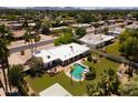 Aerial view showcases a modern home with a white roof, lush backyard pool, and an outdoor seating area at 6102 E Friess Dr, Scottsdale, AZ 85254