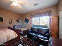 Bright bedroom with two beds, ceiling fan, a leather couch, and natural light from the window at 6535 E Superstition Springs Blvd # 217, Mesa, AZ 85206