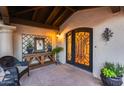 Beautiful arched front door, with decorative ironwork, and a welcoming tiled porch with seating and greenery at 6701 N Scottsdale Rd # 26, Scottsdale, AZ 85250