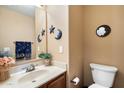 Cozy powder room featuring an updated vanity, toilet, and charming decorative accessories at 8259 W Carol Ave, Peoria, AZ 85345
