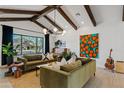Bright living room with high ceilings, exposed beams, stylish furniture, and a large window showcasing the front yard at 101 E Linger Ln, Phoenix, AZ 85020