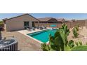Backyard swimming pool with lounge chairs, blue umbrella, and desert landscaping creates a relaxing oasis at 18388 W Ida Ln, Surprise, AZ 85387