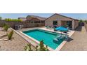 Outdoor pool area featuring a sparkling pool, desert landscaping, and a patio set for relaxing at 18388 W Ida Ln, Surprise, AZ 85387