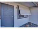 Cozy covered porch features a gray front door, gray window, and desert landscaping details at 19849 N 33Rd Ave, Phoenix, AZ 85027