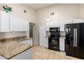 A bright kitchen features granite counters, tile floors, white cabinets and modern black appliances at 511 E Purdue Ave, Phoenix, AZ 85020
