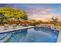 Sparkling pool boasts stone details, desert views, cascading waterfall, and comfortable lounge seating for sunset enjoyment at 9669 E Chino Dr, Scottsdale, AZ 85255