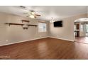 Neutral living room with wood floors, ceiling fan, TV, shelving and view into the kitchen at 13722 N 150Th Ln, Surprise, AZ 85379