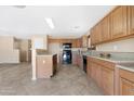 Bright kitchen featuring light wood cabinets, tile floors, black appliances, and an island with granite countertops at 1623 E Leaf Rd, San Tan Valley, AZ 85140