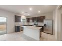 Modern kitchen with dark cabinetry, granite countertops, stainless steel appliances, and an island at 42955 W Palo Amarillo Rd, Maricopa, AZ 85138