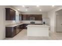 A kitchen featuring dark cabinets, stainless steel appliances, granite countertops, and tile floors at 42955 W Palo Amarillo Rd, Maricopa, AZ 85138