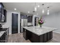 This spacious kitchen features dark cabinets, stainless appliances, a granite island, and modern lighting at 10071 W Angels Ln, Peoria, AZ 85383