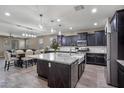 This spacious kitchen features dark cabinets, stainless appliances, a granite island, and modern lighting at 10071 W Angels Ln, Peoria, AZ 85383