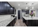 This spacious kitchen features dark cabinets, stainless appliances, a granite island, and modern lighting at 10071 W Angels Ln, Peoria, AZ 85383