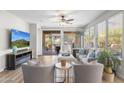 Bright living room featuring a cozy fireplace, ceiling fan, and sliding glass doors to a covered patio at 11400 E Helm Dr, Scottsdale, AZ 85255