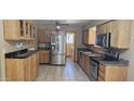 A well-lit kitchen featuring stainless steel appliances, tile flooring, and wooden cabinetry at 1586 S Lawther Dr, Apache Junction, AZ 85120