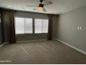 A carpeted bedroom featuring large windows with coverings and a ceiling fan at 1840 S Follett Way, Gilbert, AZ 85295