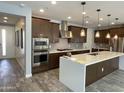 A kitchen with stainless steel appliances, dark brown cabinetry, and a large white island at 1840 S Follett Way, Gilbert, AZ 85295
