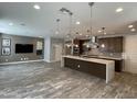 Open-concept kitchen and living room area with modern pendant lighting and stainless steel appliances at 1840 S Follett Way, Gilbert, AZ 85295