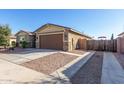 Side view of the single-story home with a two-car garage and gated side yard at 18581 W College Dr, Goodyear, AZ 85395