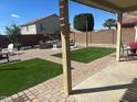 Large backyard featuring an inviting patio, well-maintained artificial grass, brick pavers, and mature landscaping at 18629 W Fulton St, Goodyear, AZ 85338