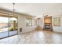 Bright living room with tile flooring, a stone fireplace, and a sliding glass door to the patio at 2762 E Clifton Ave, Gilbert, AZ 85295