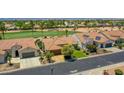 Inviting single-Gathering home with a tile roof, solar panels, lush green lawns, and mature trees bordering a golf course at 3702 N 160Th Ave, Goodyear, AZ 85395