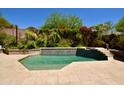 Sparkling pool with lush landscaping, and a decorative retaining wall at 9842 E Celtic Dr, Scottsdale, AZ 85260