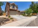 Two-story home featuring a stone facade and arched garage entrance with a concrete driveway at 13420 W Berridge Ln, Litchfield Park, AZ 85340