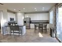 Spacious kitchen features white cabinetry, stainless steel appliances, and an island with bar seating at 20217 W Desert Bloom St, Buckeye, AZ 85326