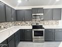 This kitchen offers stainless steel appliances, quartz countertops, and gray cabinetry at 22261 W Tonto St, Buckeye, AZ 85326