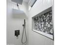 Modern shower featuring textured tile walls, pebble-style accents, and contemporary fixtures at 22261 W Tonto St, Buckeye, AZ 85326