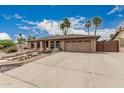 Home featuring a wide driveway, two car garage, neutral stucco, and low maintenance desert landscaping at 4229 E Pearce Rd, Phoenix, AZ 85044