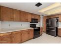 Bright kitchen boasts wooden cabinets, black appliances, and ample counter space at 6853 S Roosevelt St, Tempe, AZ 85283