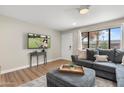 Comfortable living room with a plush gray sofa, ottoman, and natural light from a large window at 7520 E Diamond St, Scottsdale, AZ 85257