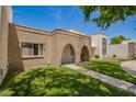 Exterior of a townhome featuring brick and beige facade, green lawn, and arched front entry at 7808 E Lewis Ave, Scottsdale, AZ 85257
