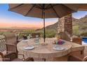 Charming outdoor dining area with a large stone table, grill, and panoramic mountain views at 11550 E Paradise Ln, Scottsdale, AZ 85255