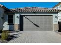 Close-up of a two car garage door with brick paver driveway and desert landscaping at 15424 N 22Nd Ln, Phoenix, AZ 85023