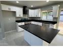 Well-lit kitchen with white cabinets, black countertops, and an island at 1720 W Michigan Ave, Phoenix, AZ 85023