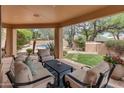 Inviting covered patio with comfortable seating that overlooks the pool and lush backyard landscaping at 23240 N Country Club Trl, Scottsdale, AZ 85255