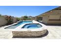 Luxurious pool and spa area with a built-in water feature, stone accents, and patio space at 28093 N Pasture Canyon Dr, San Tan Valley, AZ 85143