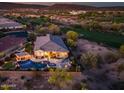 Aerial view showcasing the backyard with pool, patio, and desert landscape, backing onto a golf course at dusk at 31108 N 122Nd Ln, Peoria, AZ 85383