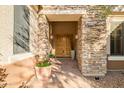 Covered entryway features stone accents with a double-door entrance and potted plants at 40123 N Majesty Trl, Anthem, AZ 85086