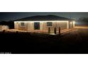 Exterior view of a newly constructed house at night, featuring stone accents and illuminated soffits at 4079 E Roosevelt St, Apache Junction, AZ 85119
