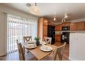 Bright dining area with wood table set for four, black appliances and view to backyard at 4642 E Sierrita Rd, San Tan Valley, AZ 85143