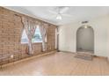 Bright living room features a brick accent wall, tile flooring, and a ceiling fan at 6430 W Thomas Rd, Phoenix, AZ 85033