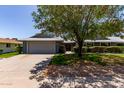 Charming single-story home featuring a spacious driveway, two-car garage, mature trees, and well-maintained landscaping at 12719 W Ashwood Dr, Sun City West, AZ 85375