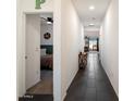 Clean, bright hallway with dark tile flooring leads to bedrooms and the living area with view to outside at 25119 N 134Th Dr, Peoria, AZ 85383