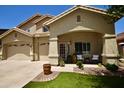 Inviting home featuring a charming front porch and well-manicured lawn and three-car garage at 44236 W Adobe Cir, Maricopa, AZ 85139