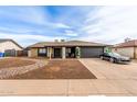 Inviting single-story home with a black two-car garage and modern desert landscaping at 4441 W Windrose Dr, Glendale, AZ 85304